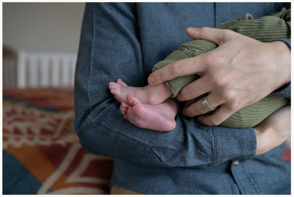 a close up photo of tiny baby feet being held in dad's arms.